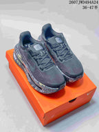 Pair of black and gray Nike Air Pegasus Premium sneakers displayed on an orange shoebox, showing multicolor splatter-style midsoles.