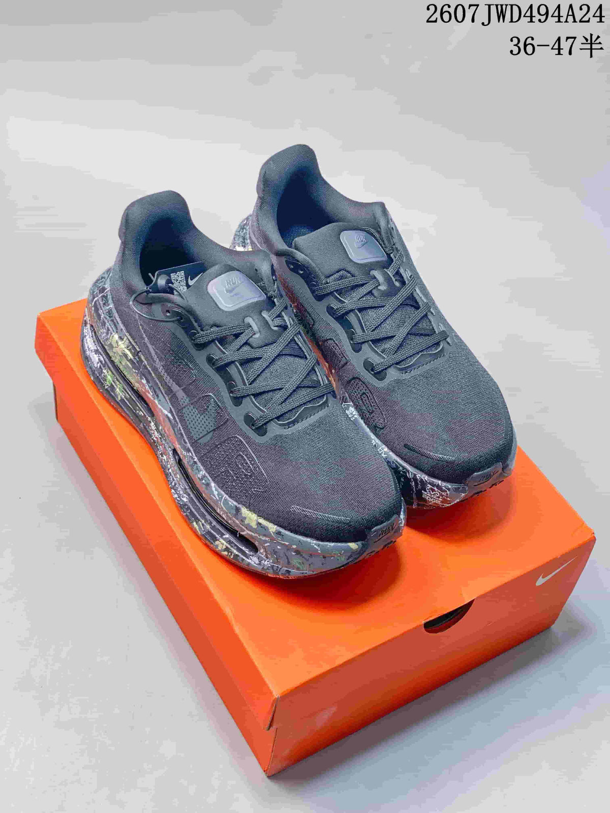 Pair of black and gray Nike Air Pegasus Premium sneakers displayed on an orange shoebox, showing multicolor splatter-style midsoles.