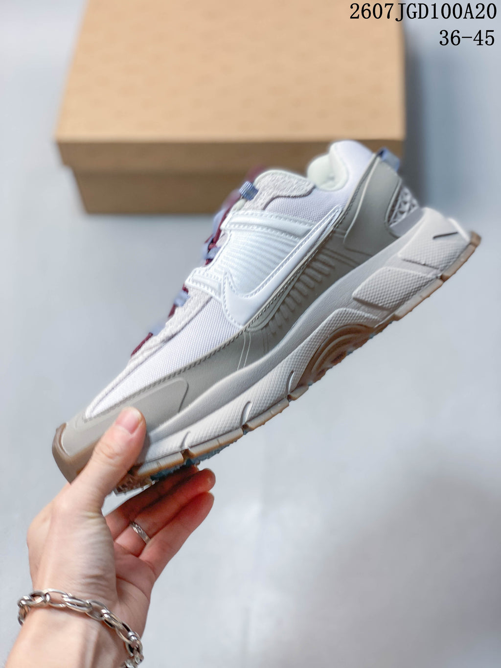 Side profile of the white and grey Nike sneaker showing layered overlays, a Swoosh logo, reinforced heel area and segmented outsole.