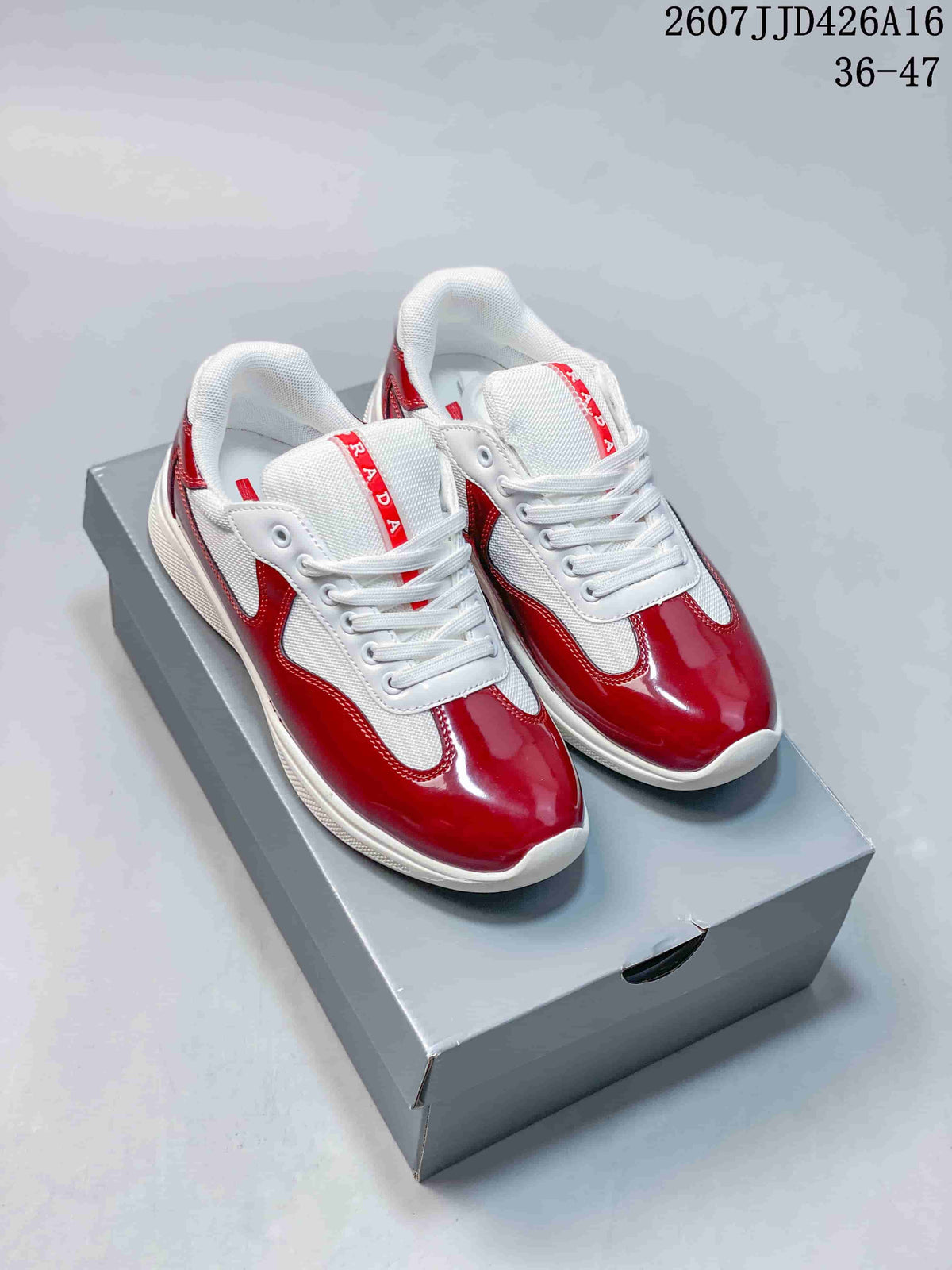 Pair of red and white Prada-branded platform sneakers displayed on a gray shoebox; style code 2607JJD426A16 and size range 36–47 are visible.