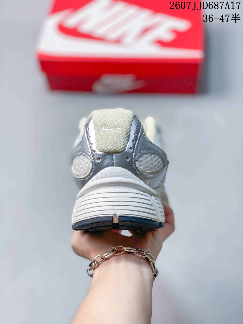 Rear view of the white and silver sneaker showing the padded heel, tongue and layered sole.