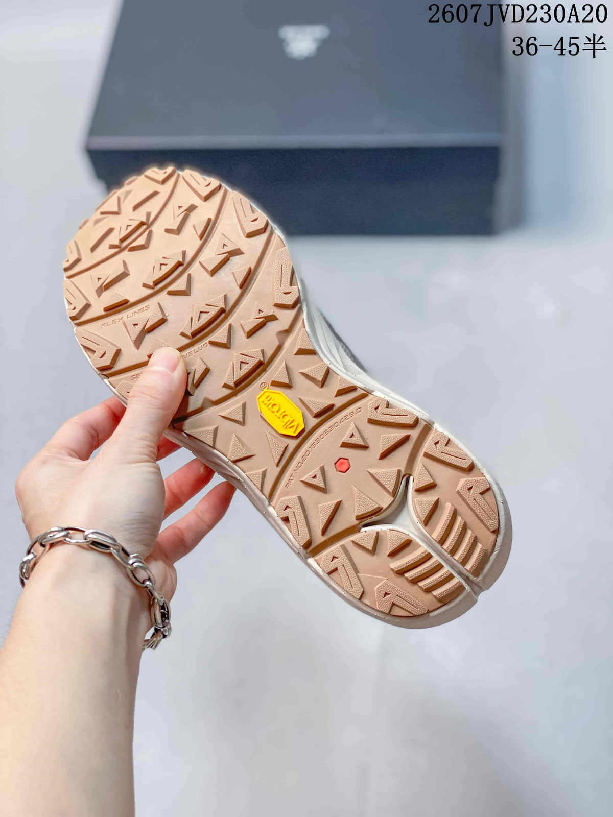 Close view of the tan-colored outsole with multidirectional lug patterns and a visible yellow outsole insert.