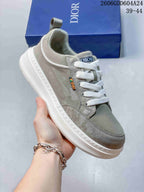 Angled close-up of a gray-green Dior sneaker with visible tongue and side branding