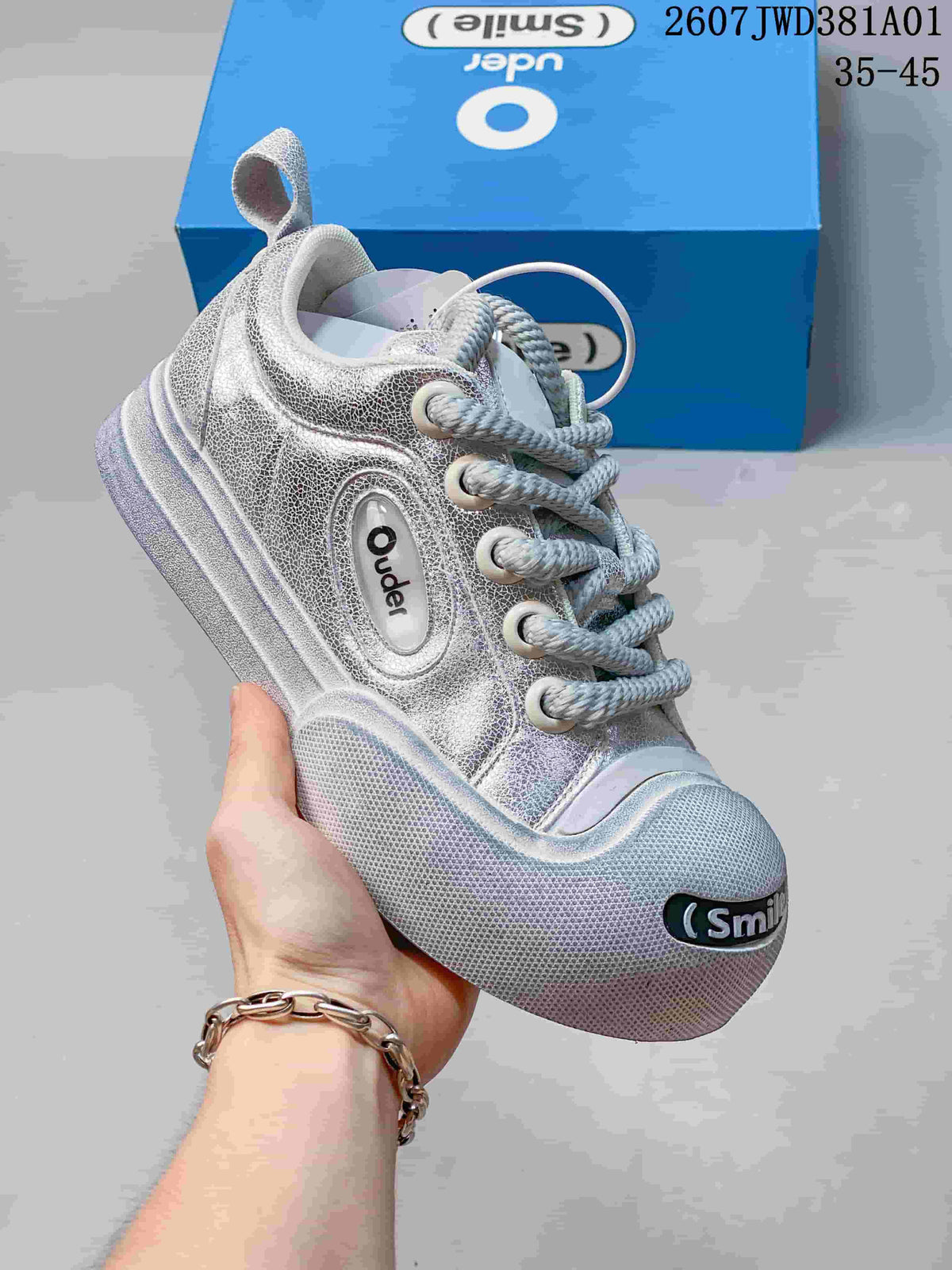 Close-up of a silver Ouder sneaker showing rope laces, textured panels, and Smile toe detail.