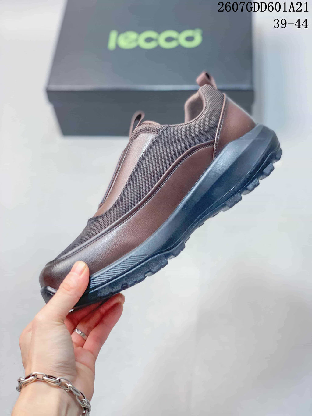 Side profile of the brown ECCO slip-on shoe showing textile panels, contrasting trim, and the raised lugged outsole.