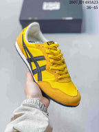 Close side view of a yellow Onitsuka Tiger Serrano sneaker with dark stripes.