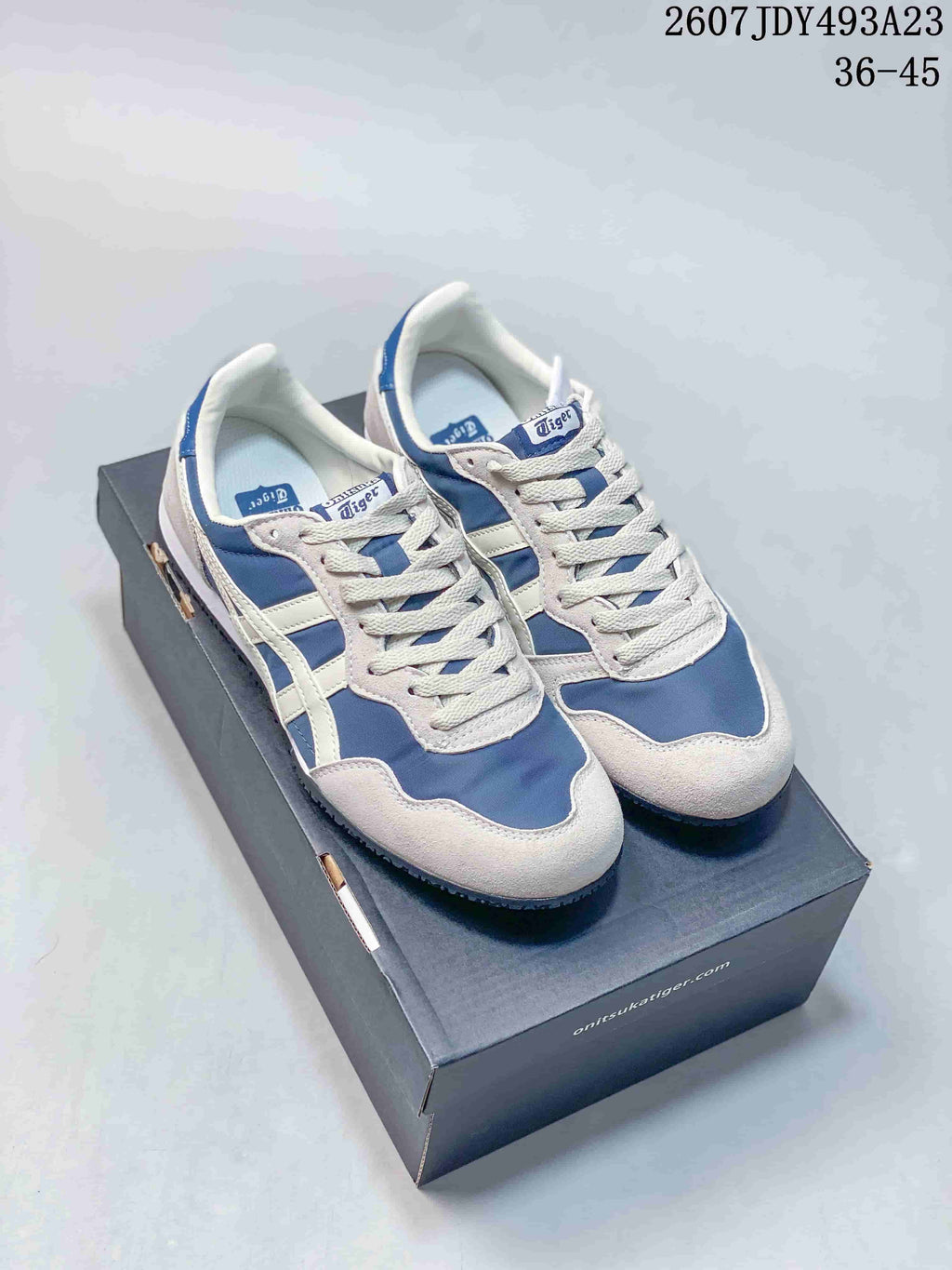 Pair of white and blue Onitsuka Tiger Serrano sneakers shown from above on a shoe box.