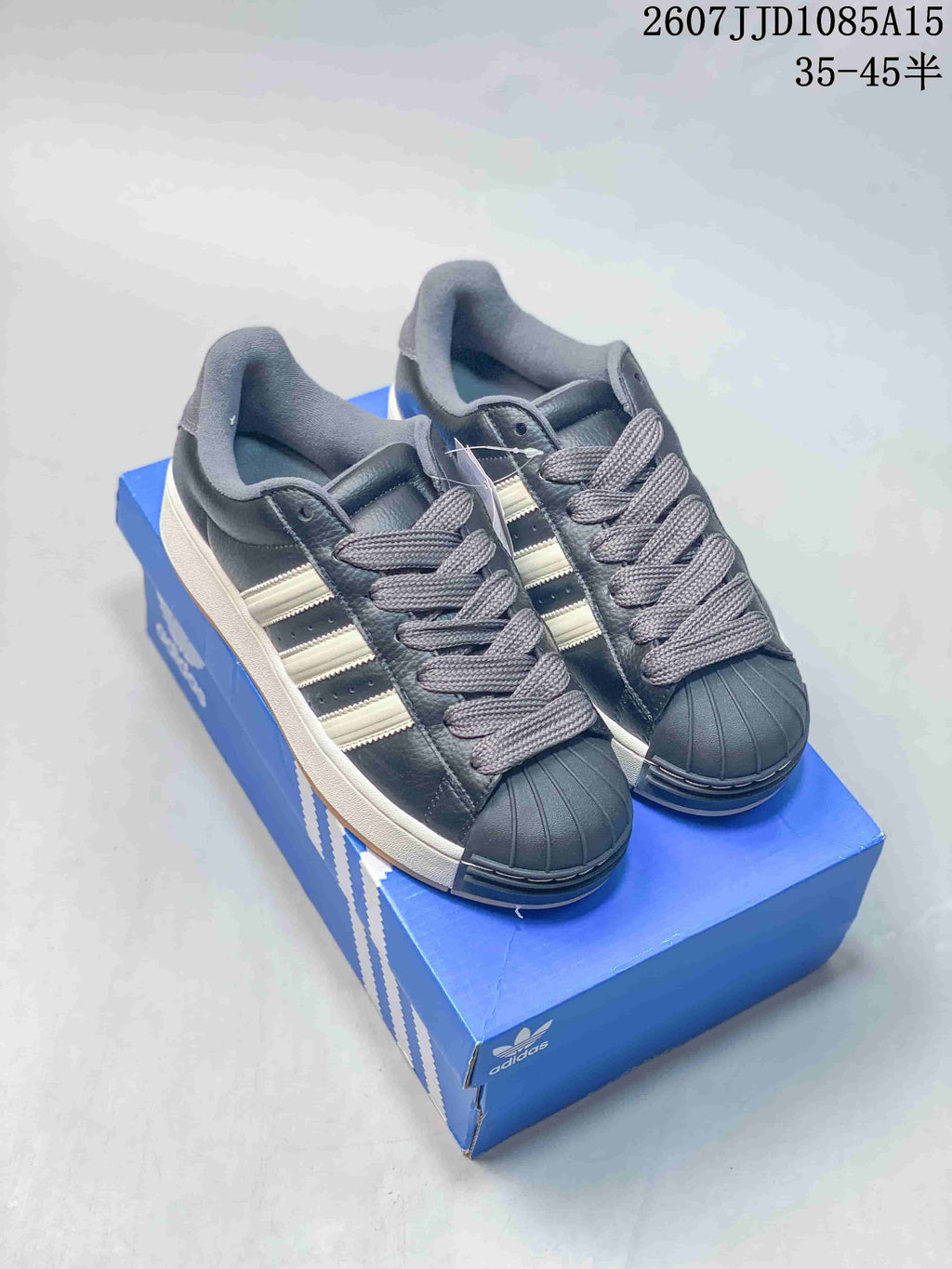 Pair of black adidas Superstar XLG sneakers with light stripes, gray laces, shell-style toe caps, and a blue shoebox.