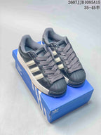 Pair of black adidas Superstar XLG sneakers with light stripes, gray laces, shell-style toe caps, and a blue shoebox.