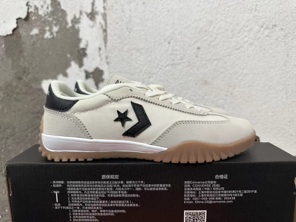 Side profile of a cream Converse sneaker with a black star-and-chevron logo and ridged gum outsole