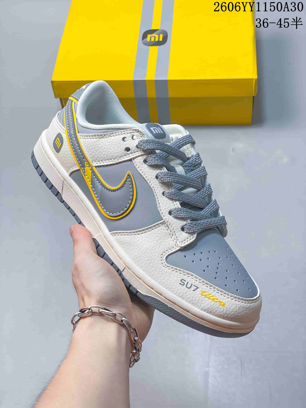 Close-up side view of a grey, white, and yellow Nike SB Dunk Low sneaker