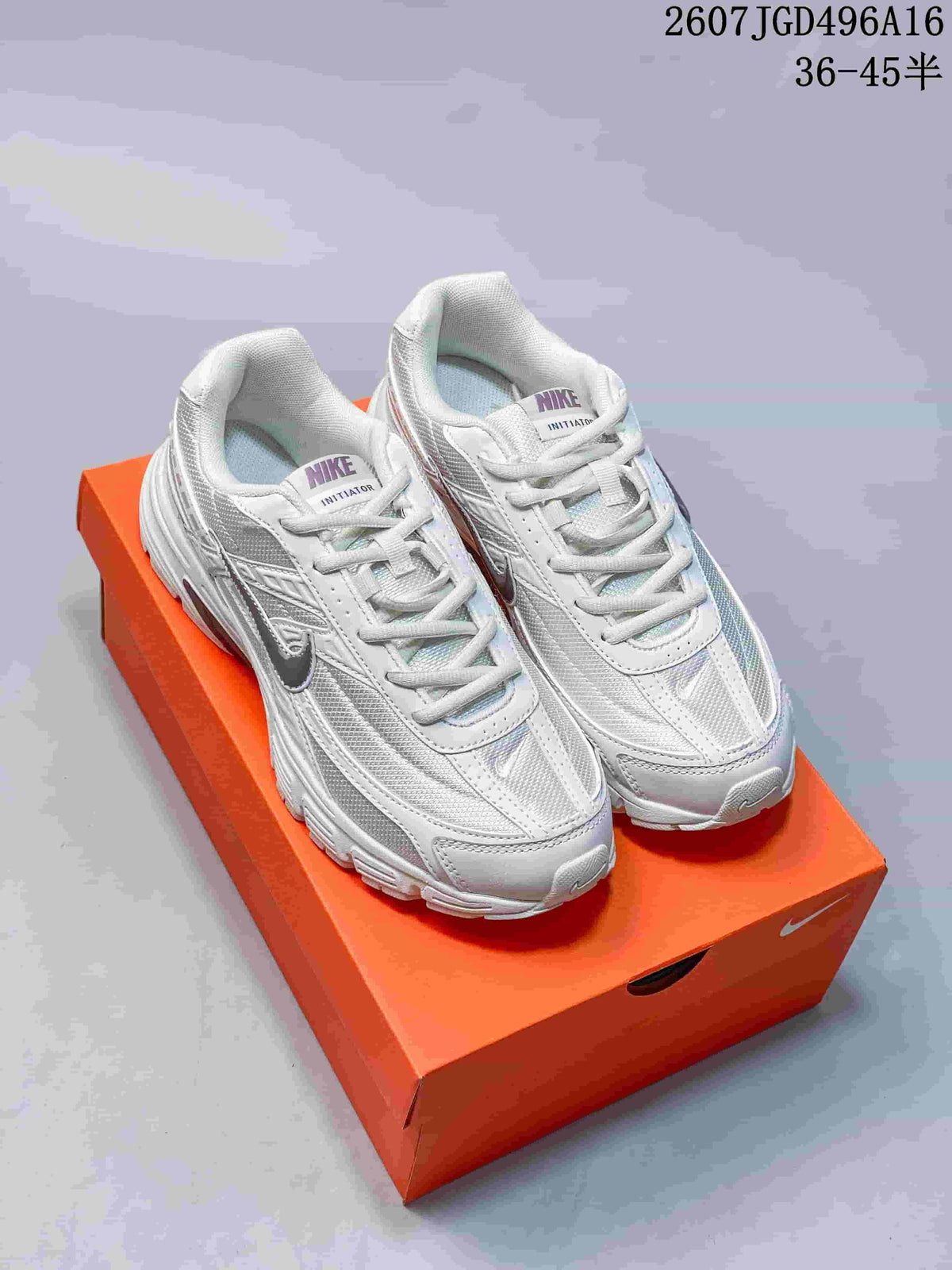 Pair of white and grey Nike Initiator sneakers displayed on an orange shoebox; overlay text shows 36–45 sizing.