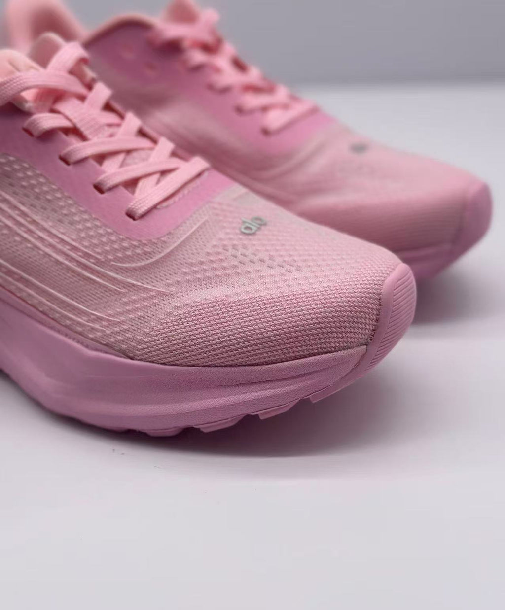 Close-up of the pink sneaker toe box, laces, textured surface, and visible Alo branding.