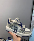 Cream and navy MLB low-top sneaker with repeated B-pattern panels, large side B graphics, contrast laces, and a front strap.