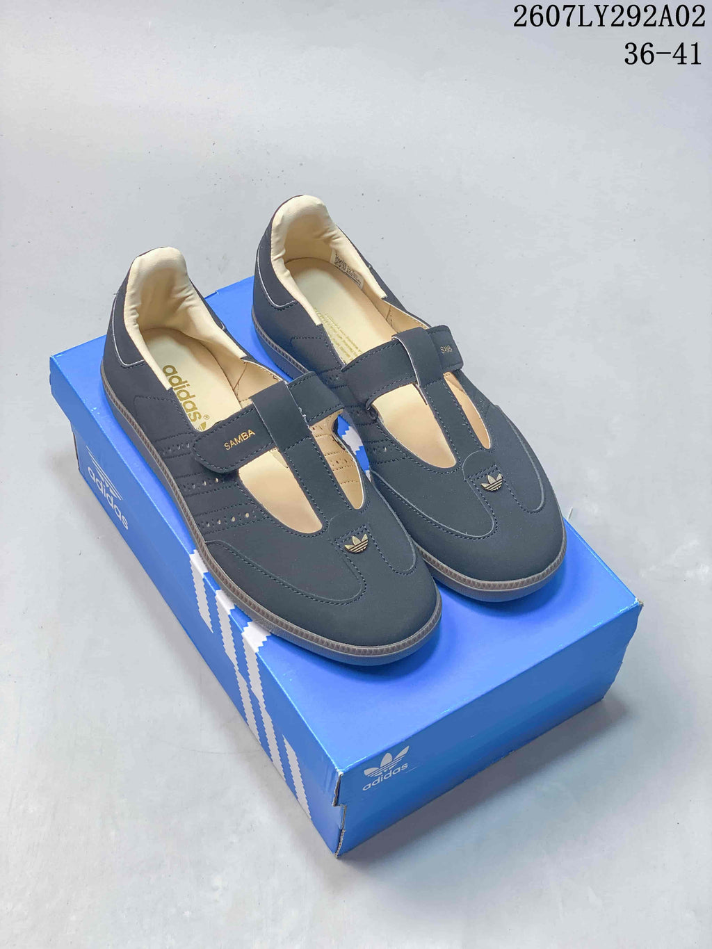 Dark Adidas Originals Samba Jane sneakers displayed on a blue shoebox with cream interiors and contrasting outsoles.