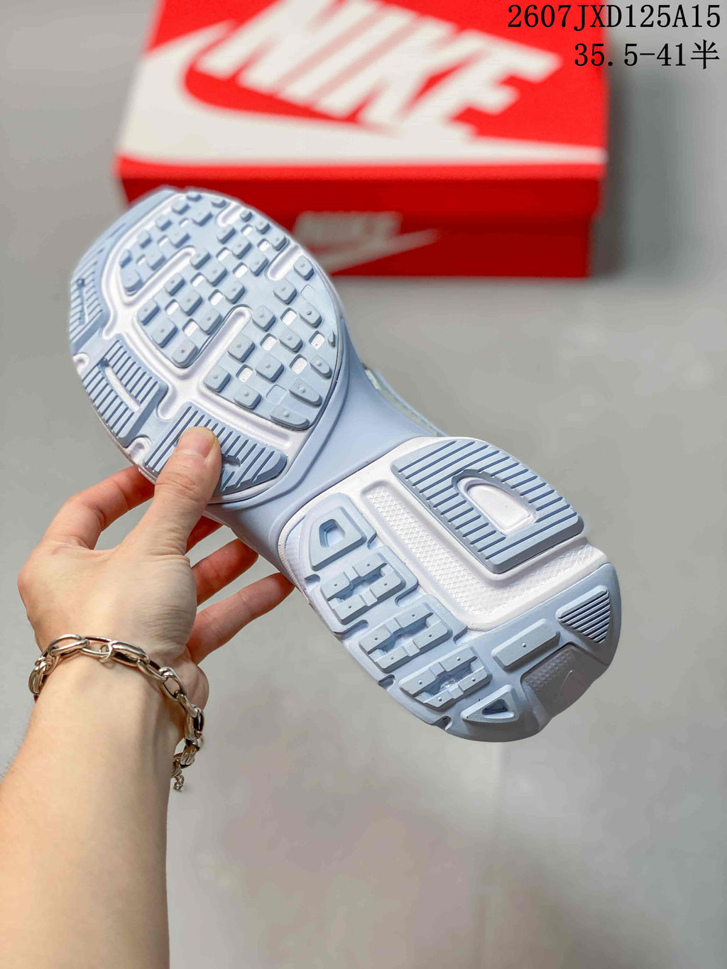 Close view of the textured outsole and tread pattern on a white and silver sneaker.