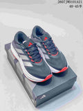 Pair of dark gray Adidas sneakers with white side stripes, red accents, and a white midsole displayed on a shoe box.