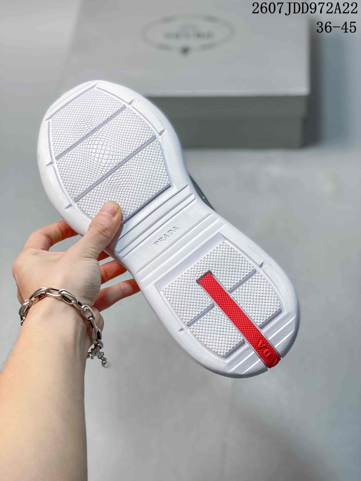 Close view of the textured white outsole with Prada branding and a red heel strip.