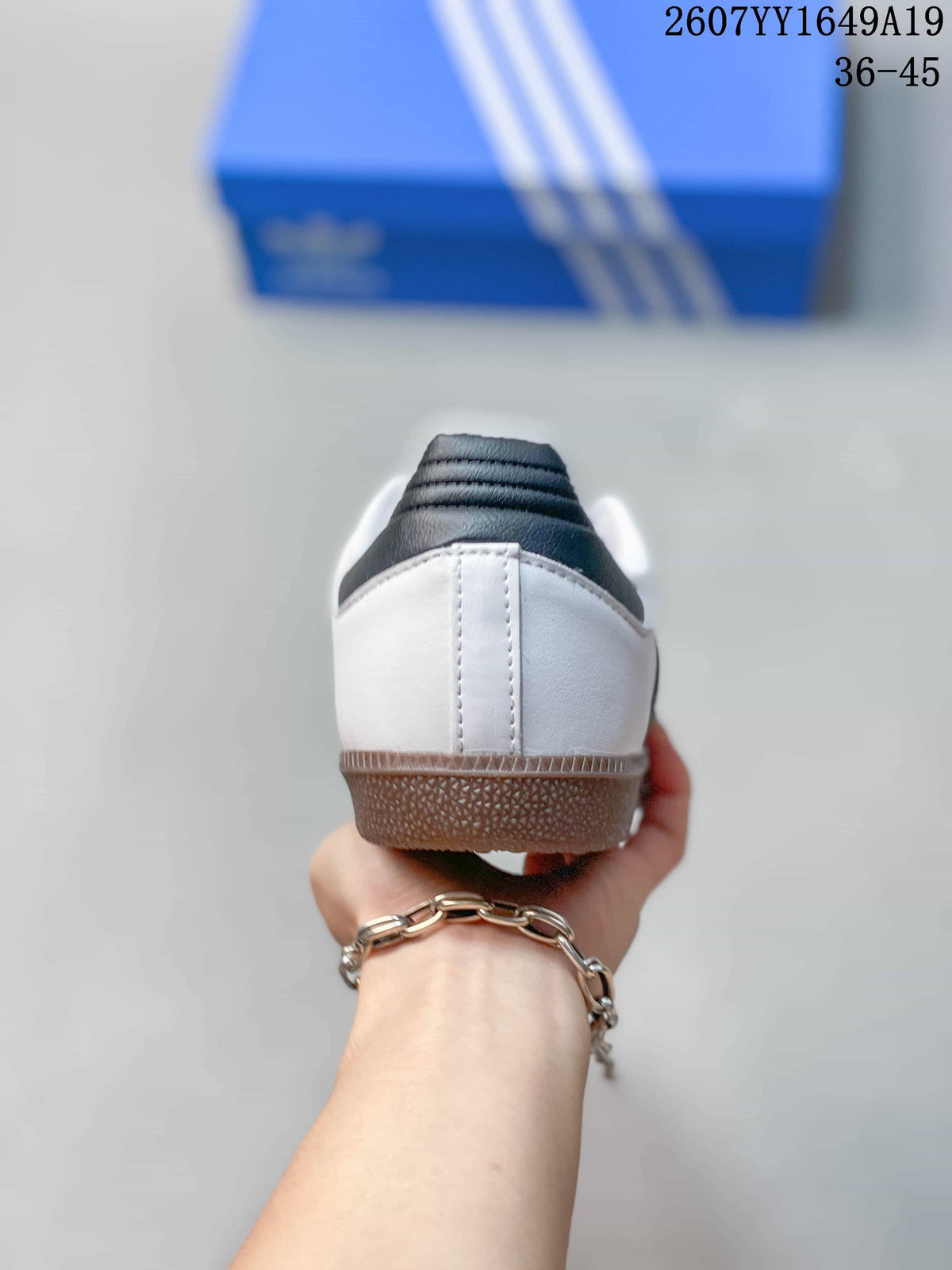Rear view of the white sneakers showing the padded black-and-white heel collars and gum-colored heel sections.