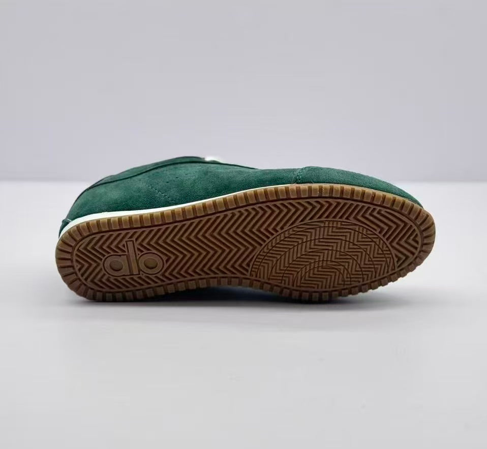 Underside view of a green Alo sneaker showing the brown outsole and patterned tread.