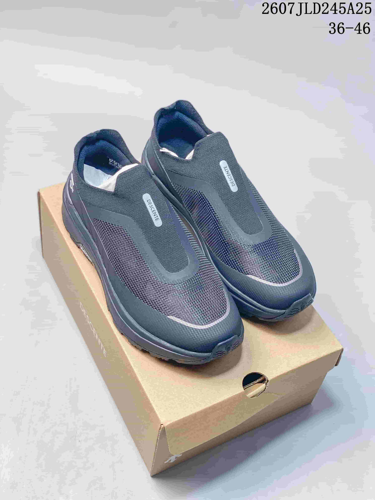 Pair of dark navy and black DESCENTE slip-on sneakers displayed on a shoe box; image text shows style code 2607JLD245A25 and size range 36–46.