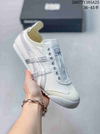 White Onitsuka Tiger slip-on sneaker with pale gray side stripes and matching outsole details.