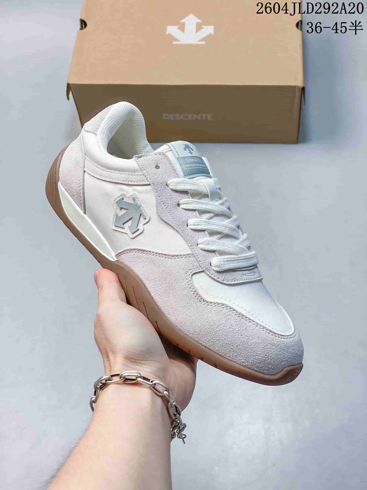 Angled side view of the light-colored sneaker, with its side emblem, layered upper and gum-colored sole visible.