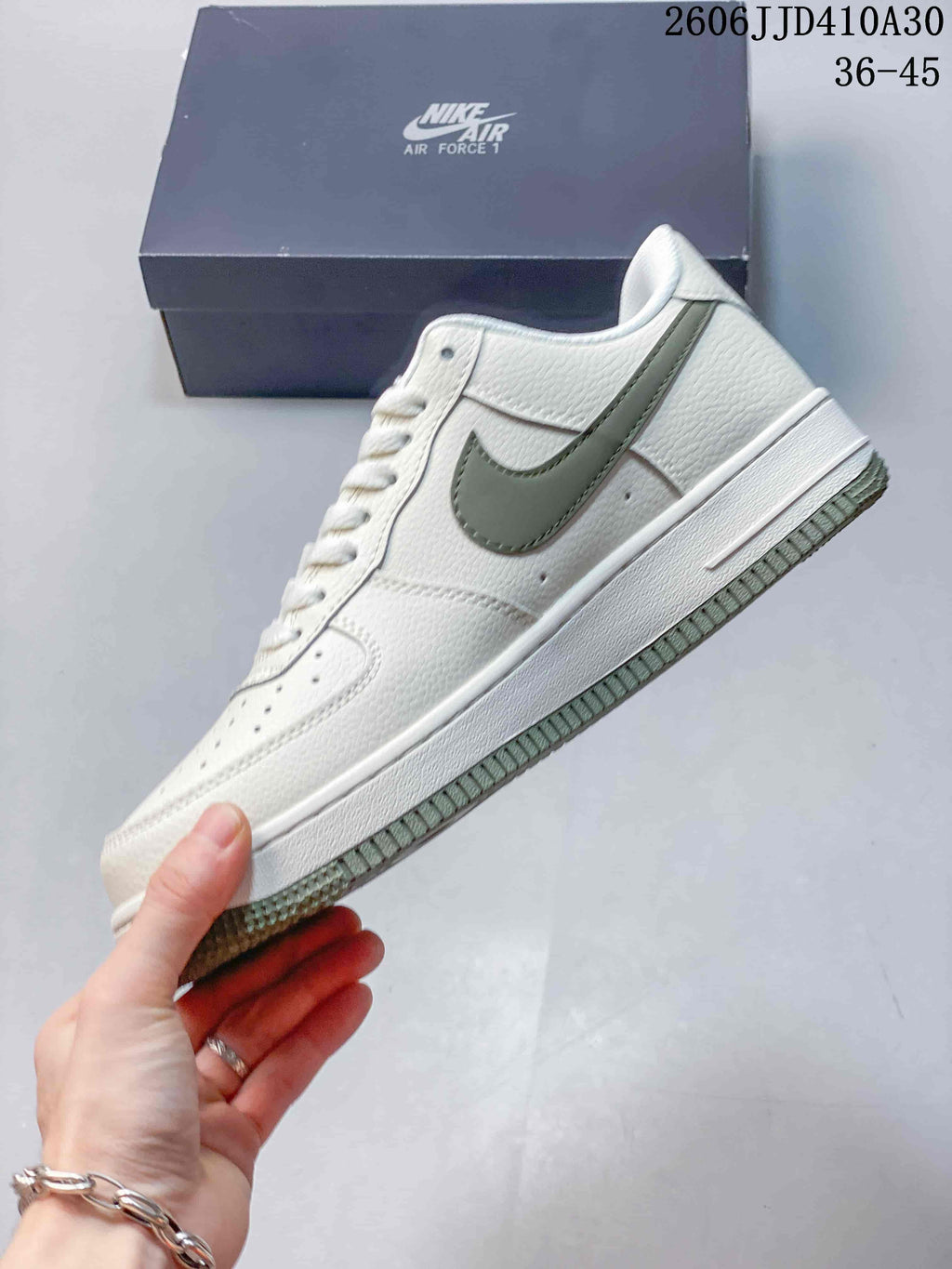 Side view of the low-top sneaker with a sage-green swoosh and white upper