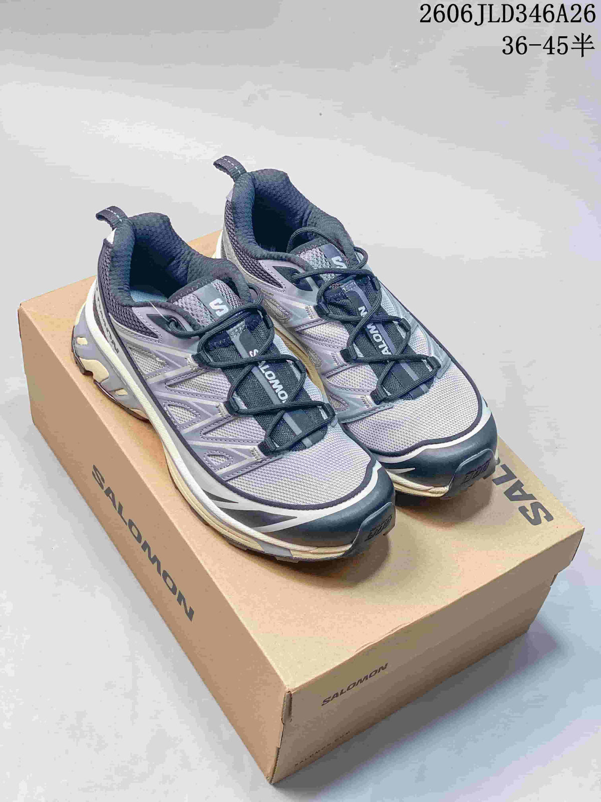 Pair of gray and dark navy Salomon XT-6 sneakers displayed on a Salomon shoebox
