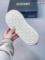Underside view of the white sneaker showing its repeating geometric outsole texture.