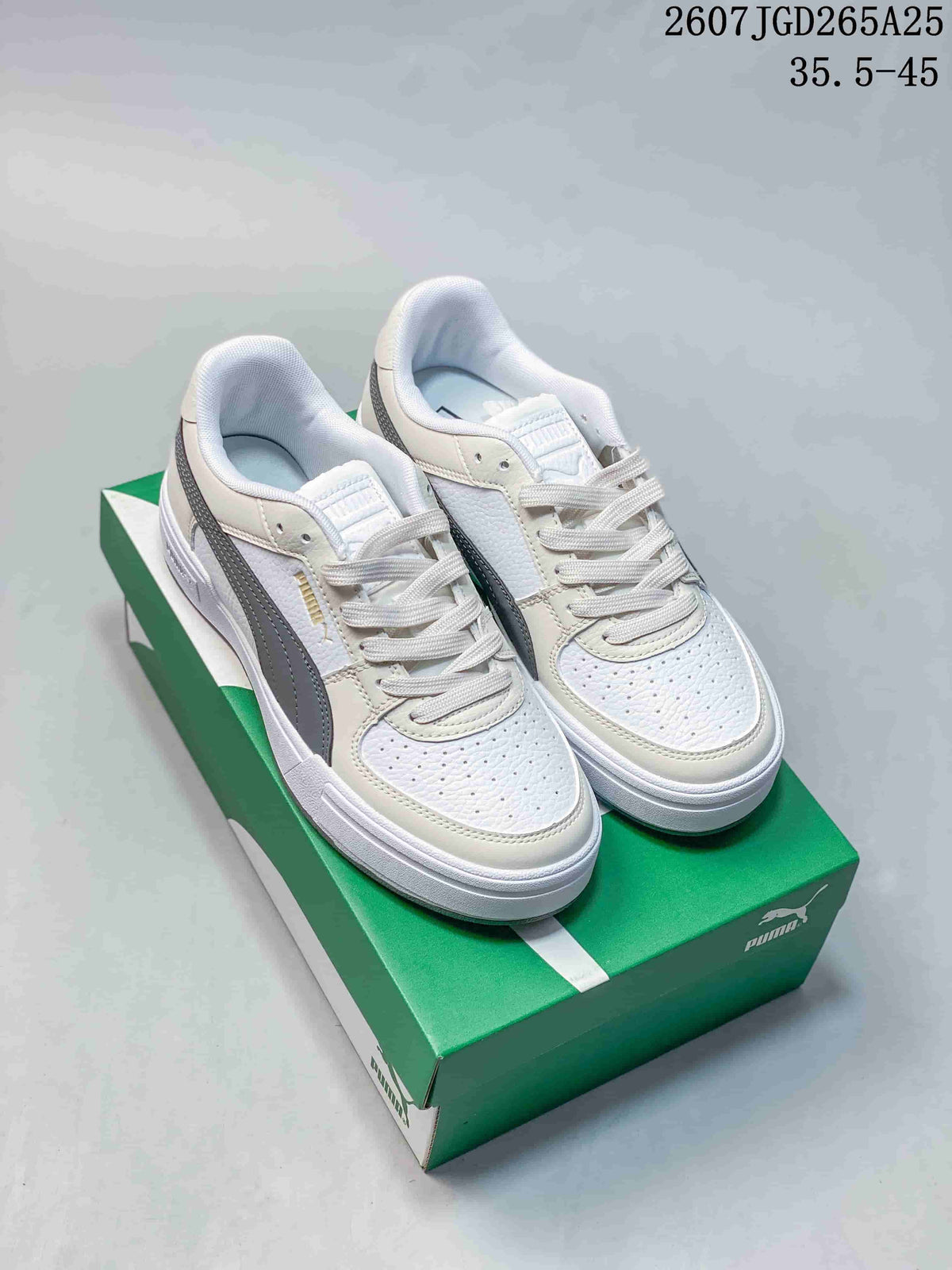 Pair of white and gray PUMA low-top sneakers displayed on a green shoebox.