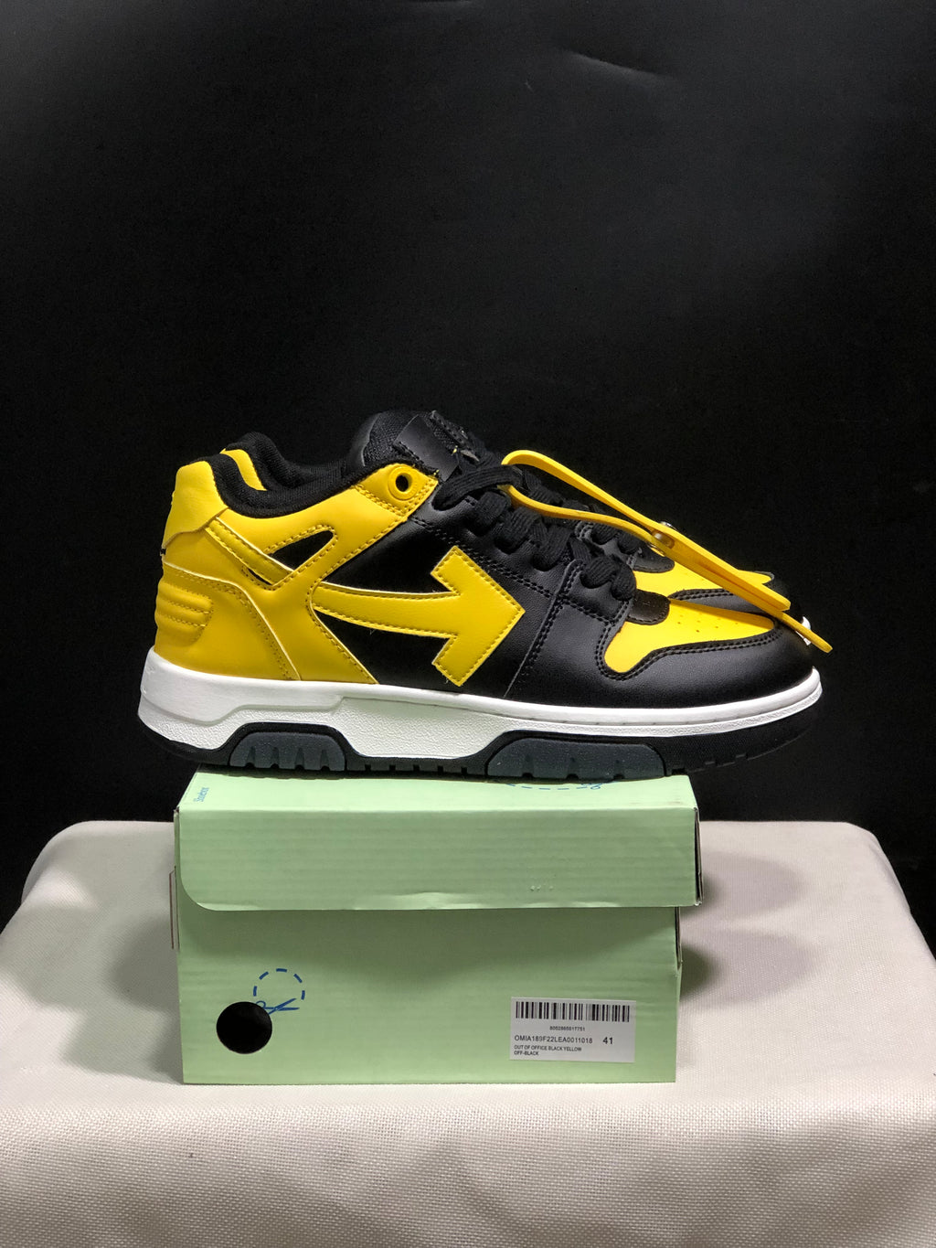 Side view of a black and yellow low-top sneaker with yellow detailing, white midsole, and black outsole.