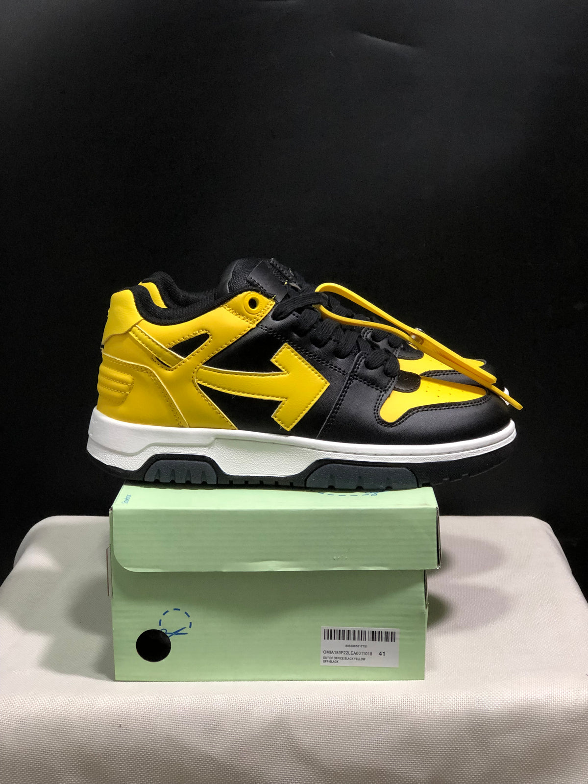 Side view of a black and yellow low-top sneaker with yellow detailing, white midsole, and black outsole.