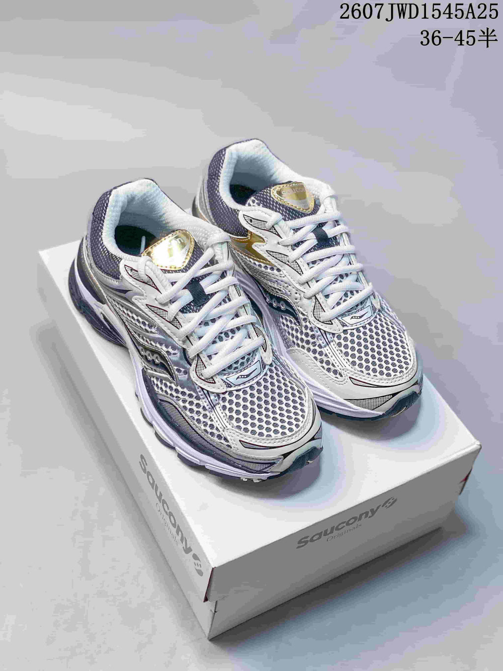 Pair of Saucony Pro Grid Omni 9 sneakers in white, silver, gold and dark navy displayed on a Saucony shoebox.