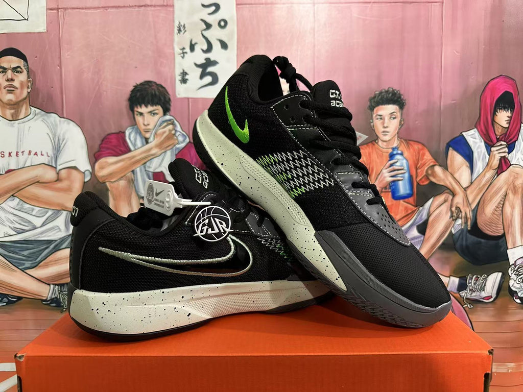Angled view of a pair of black Nike basketball shoes showing the green Swoosh, contrasting side pattern and speckled midsoles.