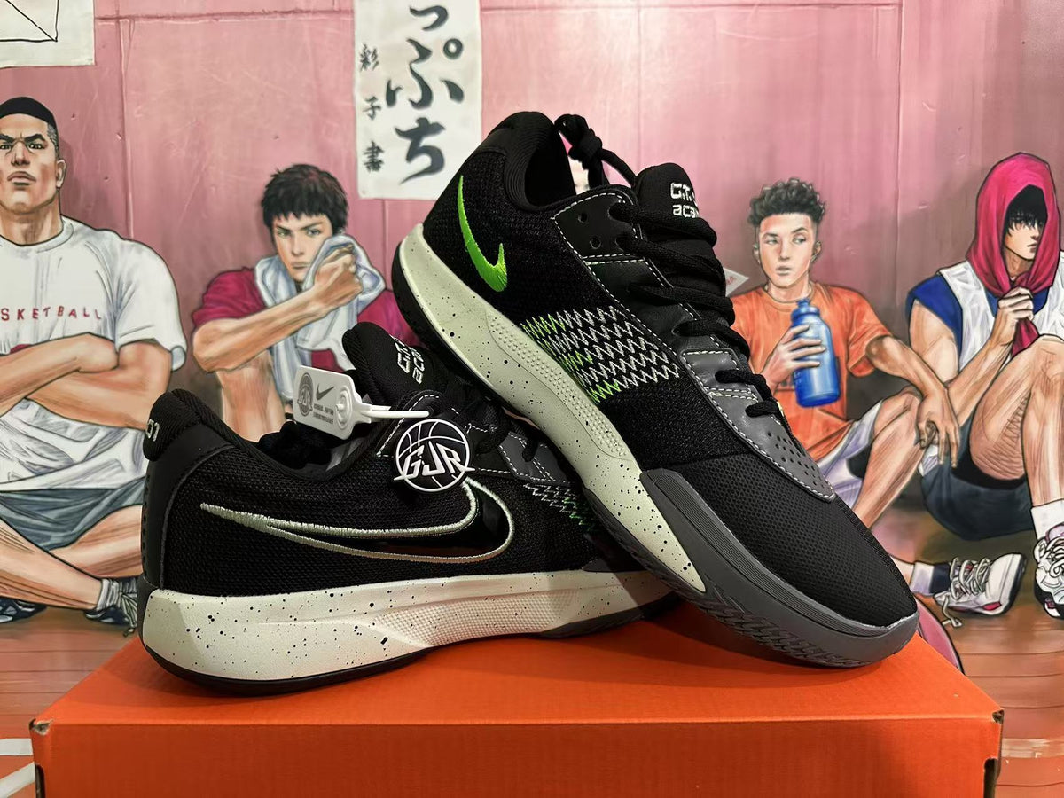 Angled view of a pair of black Nike basketball shoes showing the green Swoosh, contrasting side pattern and speckled midsoles.