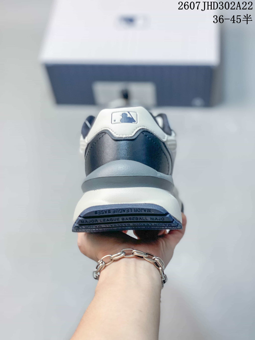 Rear view of the sneaker showing the navy heel panel, white collar detail, thick midsole, and outsole markings.