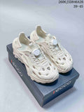 White perforated closed-toe shoes with cord-style lacing and chunky soles, displayed on a branded box.