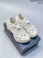 White perforated closed-toe shoes with cord-style lacing and chunky soles, displayed on a branded box.