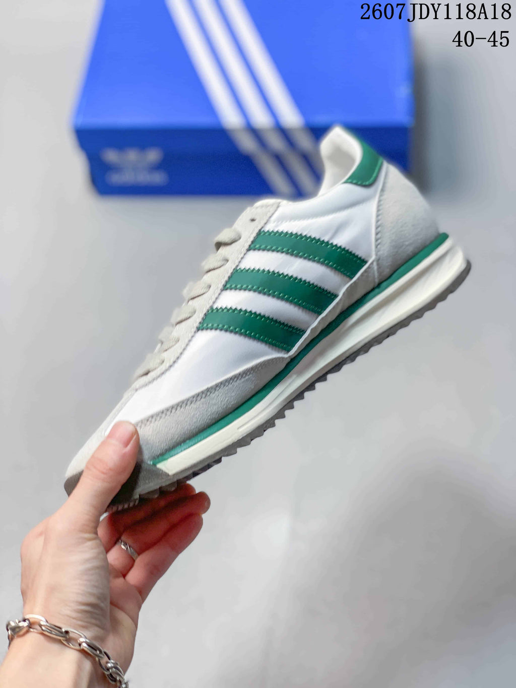 Side view of the white and green sneaker showing the three green stripes, suede-look overlays, and layered low-profile sole.