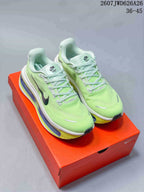 Pair of bright green Nike sneakers displayed on an orange shoebox, showing black Swoosh branding and layered colorful soles.