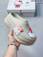 Angled view of a cream adidas x Hello Kitty mule clog with raised sole and character graphics