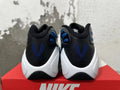 Rear view of blue, black, and white Nike sneakers with blue heel embroidery and a white sculpted midsole.