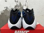 Rear view of blue, black, and white Nike sneakers with blue heel embroidery and a white sculpted midsole.