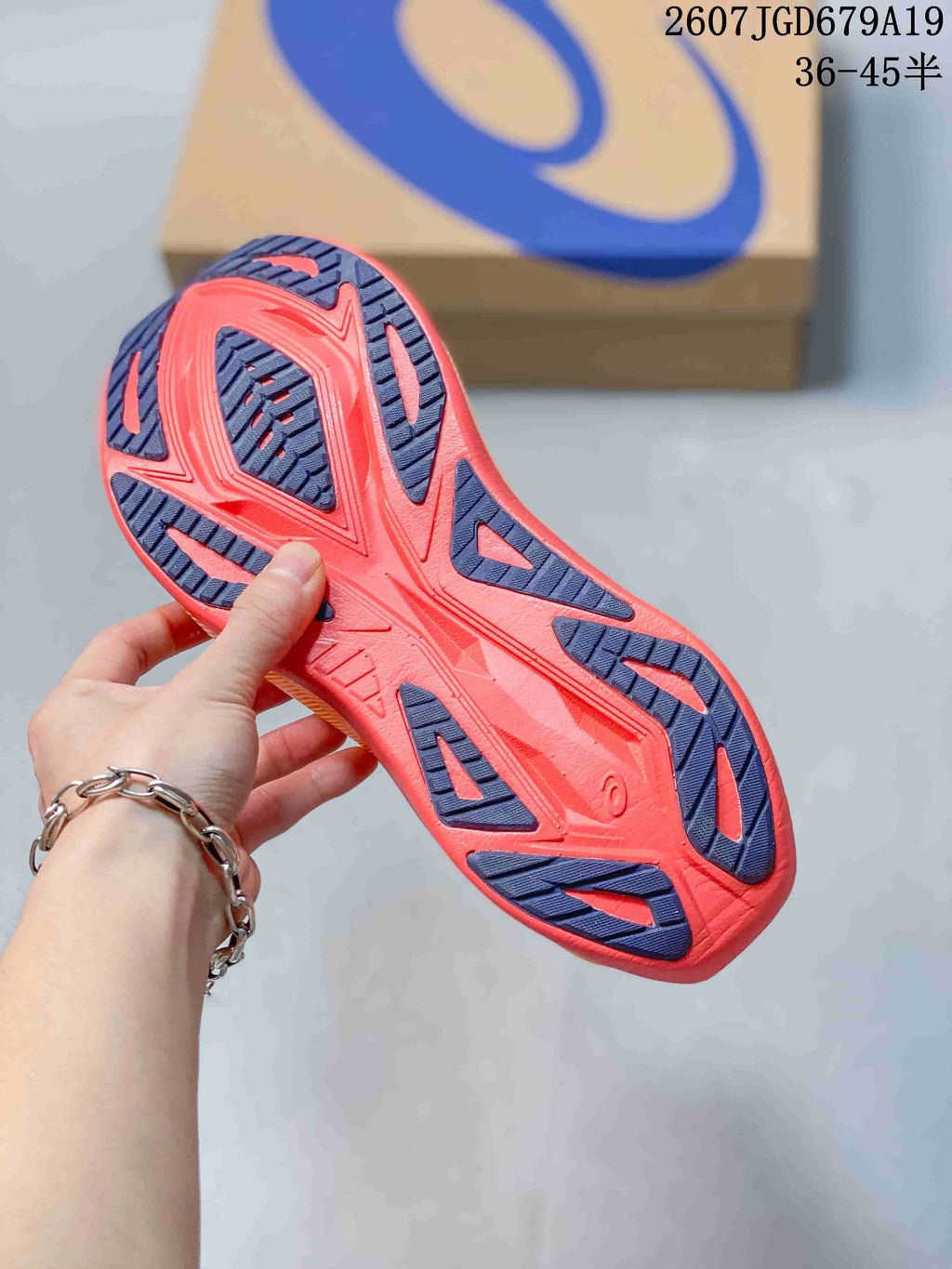 Bottom view of the sneaker showing the coral and dark blue segmented outsole pattern.