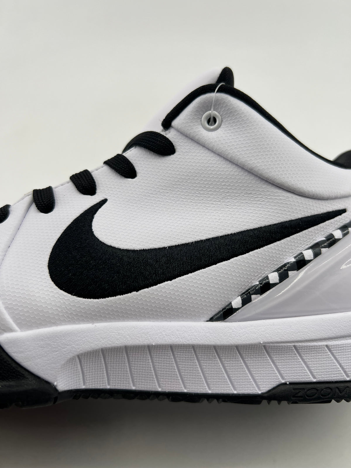 Side close-up of the black Swoosh, checkerboard trim, and white midsole