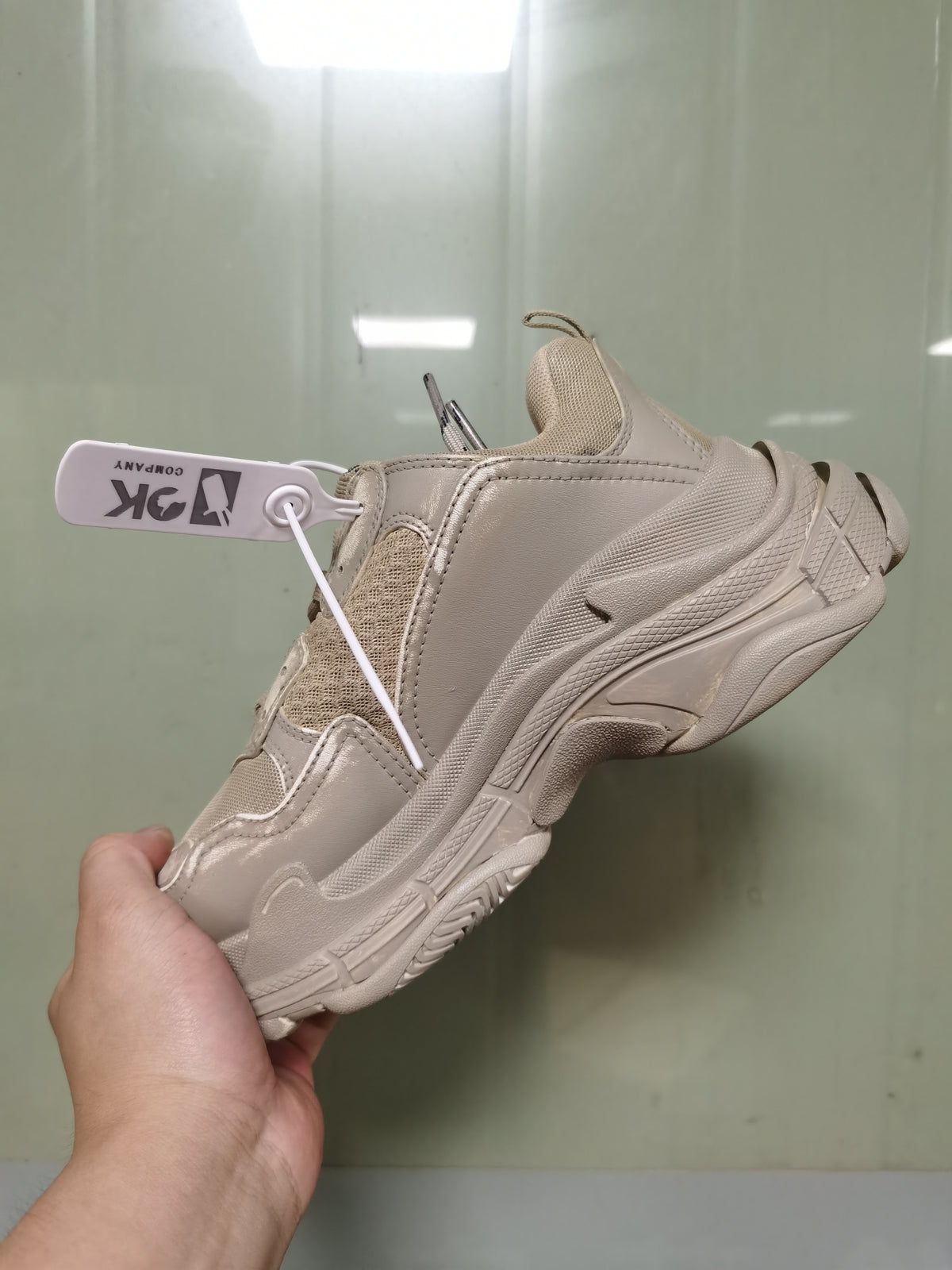 Rear-side view of the light beige Balenciaga Triple S sneaker showing the layered heel structure, mesh panel, and textured outsole.