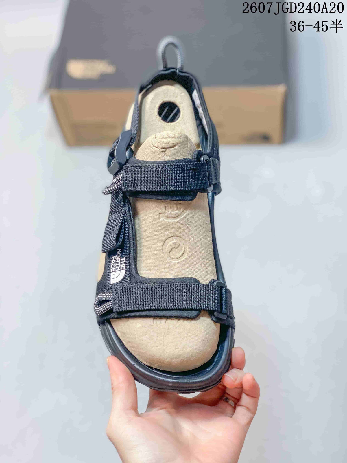 Top view of the open-toe sandal showing the tan footbed, black straps, buckles, and The North Face branding.