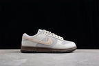 Side view of the light gray and off-white low-top sneaker against a black background.