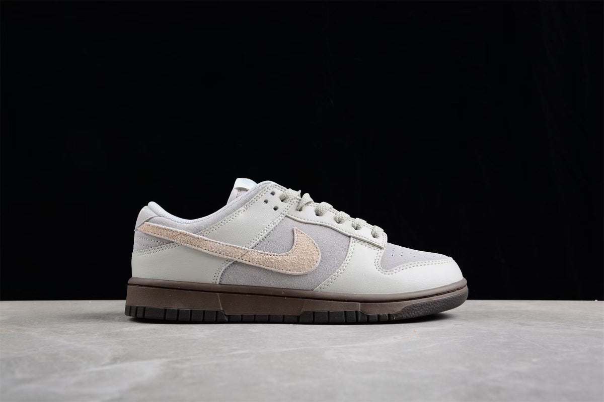 Side view of the light gray and off-white low-top sneaker against a black background.